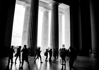 Black and White Photo inside the Abraham Lincoln memorial with silhouettes of the visitors walking.