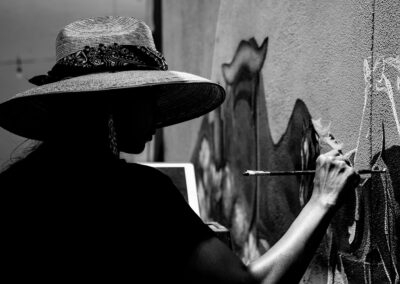 Black and white photo of artist La Morena while she is painting her mural at the Miraval Resort is Tucson, Marana, Arizona.
